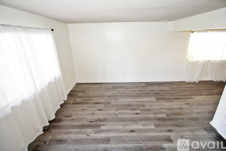 A room with wooden flooring and white curtains.