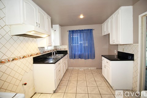 A kitchen with white cabinets and a black countertop.