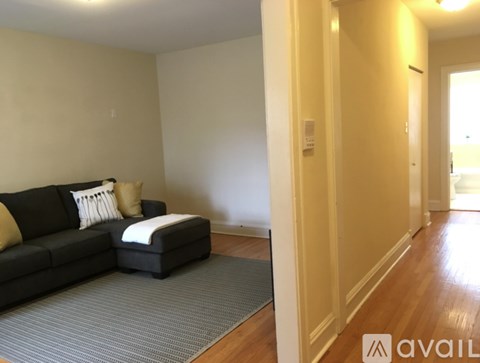 A living room with a black couch and a grey rug.