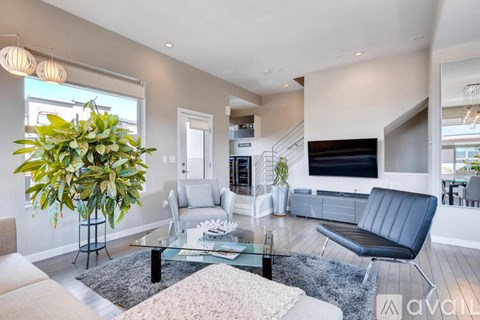 A living room with a black leather sofa and a glass coffee table.