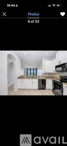 A kitchen with white cabinets and a black countertop.