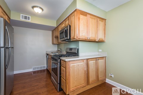 A kitchen with wooden cabinets and a stainless steel refrigerator.