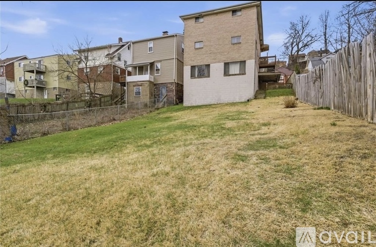 A grassy area in front of apartment buildings with a fence on the right side.
