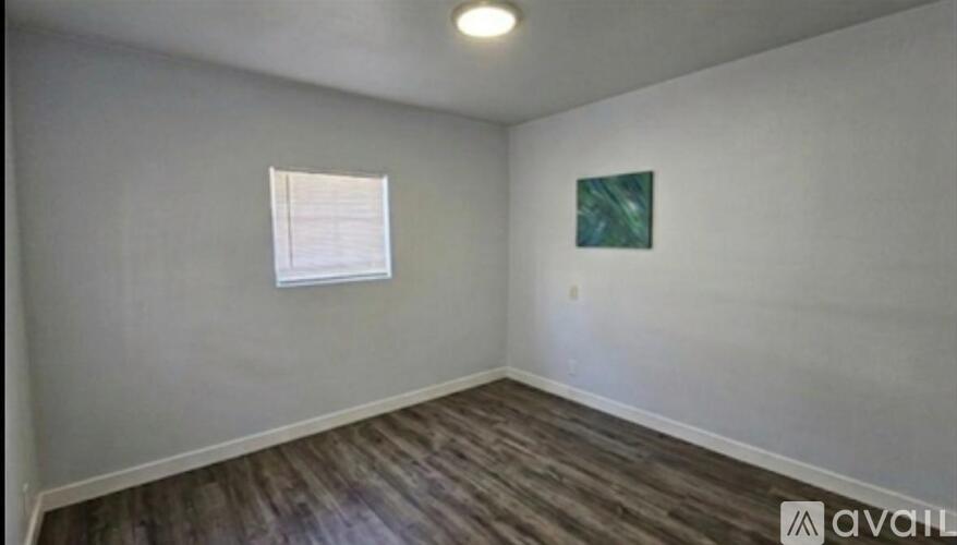 A room with a wooden floor and a painting on the wall.