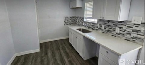 A kitchen with white cabinets and a sink.