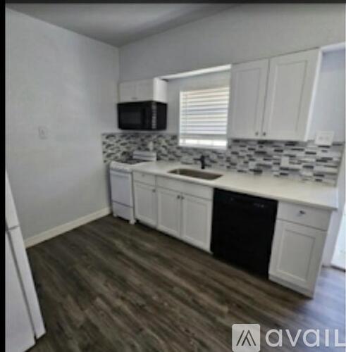 A kitchen with white cabinets and a black dishwasher.