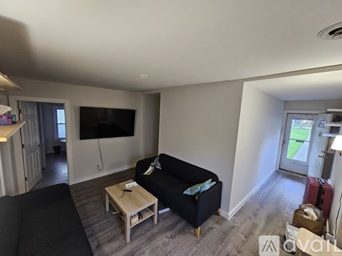 A living room with a black couch and a flat screen TV mounted on the wall.