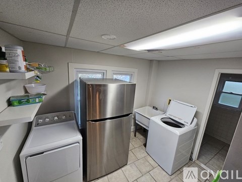 A small laundry room with a washer and dryer, a fridge, and a toilet.