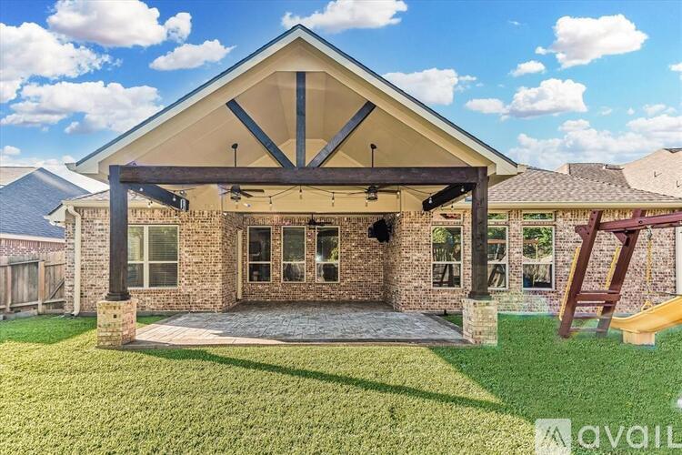 A house with a covered patio and a playground slide in the yard.