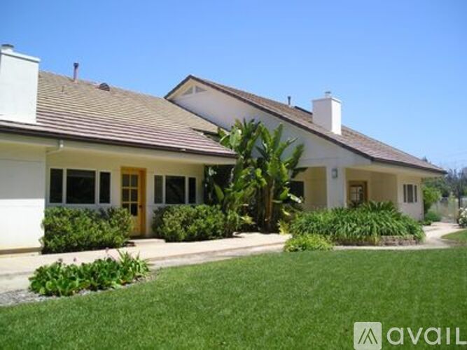 A house with a brown roof and a white wall with a yellow door.