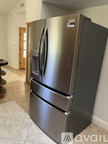 A stainless steel fridge with a black handle is in a kitchen.