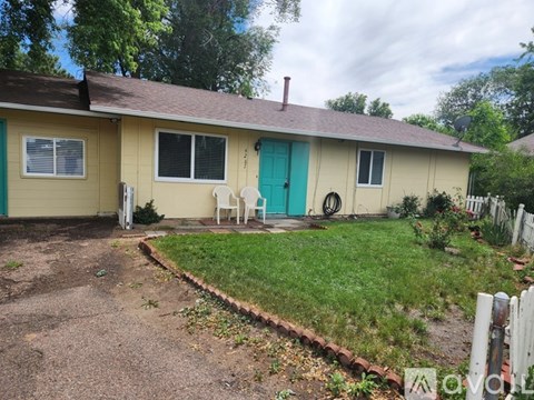 A yellow house with a blue door and a green door.