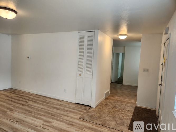 A room with wooden flooring and white walls, featuring a white door with a window above it.