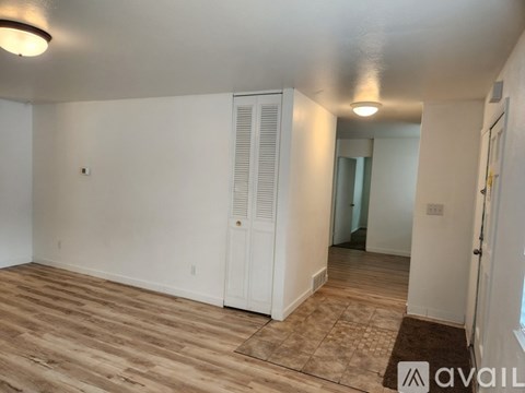 A room with wooden flooring and white walls, featuring a white door with a window above it.