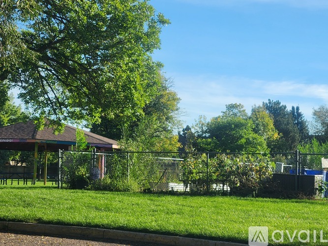 A gazebo is surrounded by a fence and greenery.