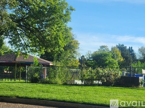 A gazebo is surrounded by a fence and greenery.