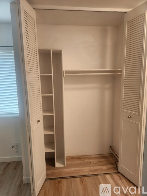 A white closet with a shelving unit and a door.