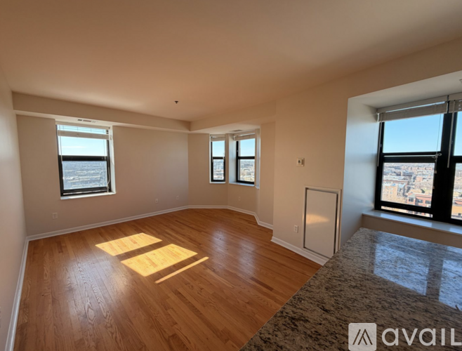 A spacious room with wooden floors and large windows.