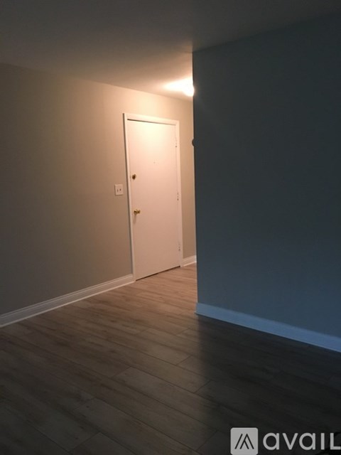 A white door is in a room with wooden floors and a wall.