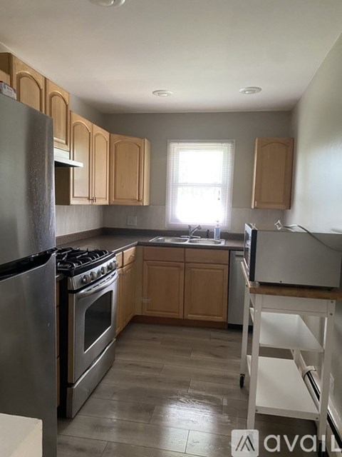 A kitchen with wooden cabinets and a stainless steel refrigerator.
