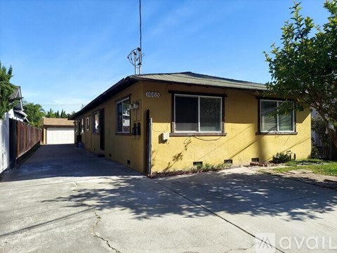 A yellow house with a black roof and a garage door.