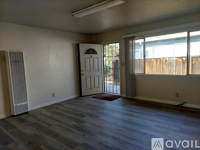 A room with a door and a window with a view of a fence.