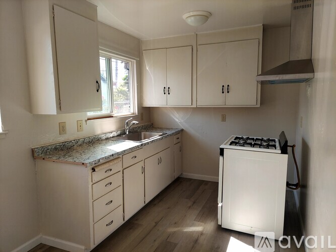 A kitchen with white cabinets and a white stove top oven.