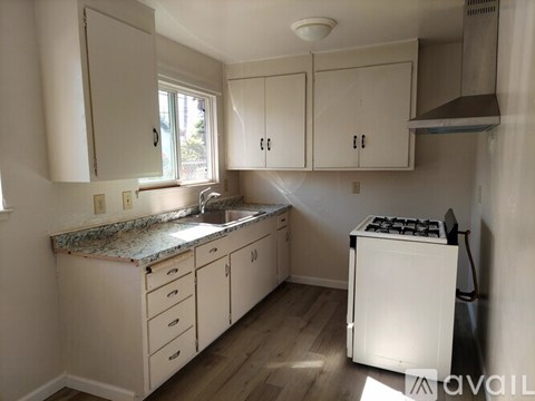 A kitchen with white cabinets and a white stove top oven.