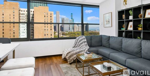A modern living room with a grey sofa and a coffee table in front of a large window overlooking a cityscape.