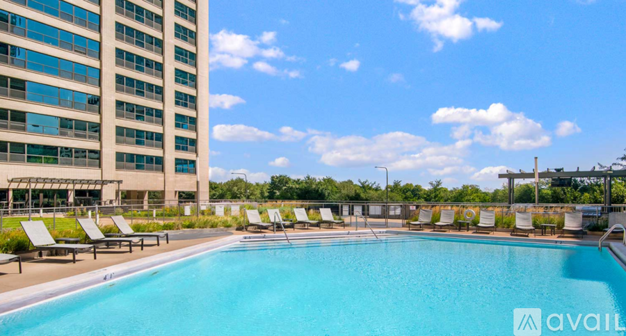 A large swimming pool surrounded by sun loungers in front of a tall building.