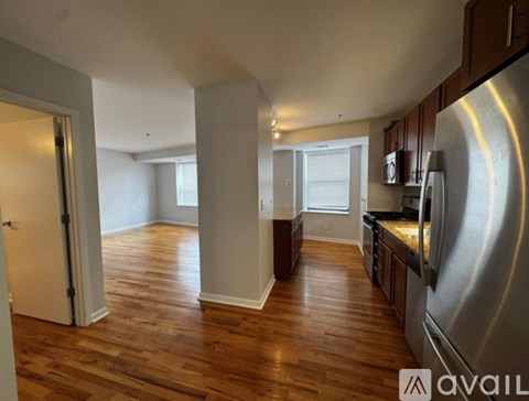 A kitchen with wooden floors and a refrigerator on the right.