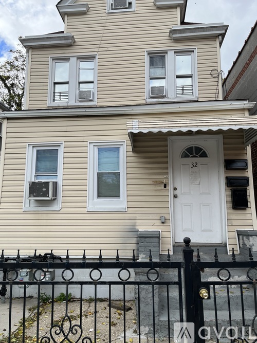 A two-story house with a white door and black iron fence.