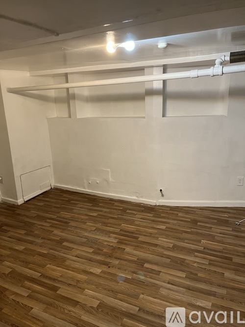 A room with wooden flooring and white walls.