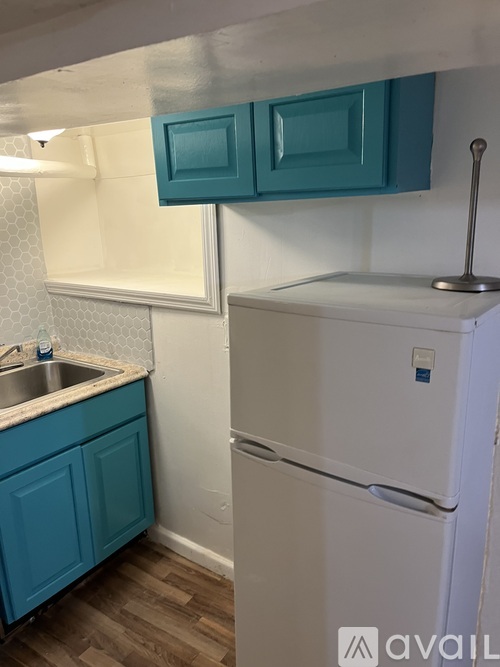 A kitchen with a white fridge and a blue cabinet.