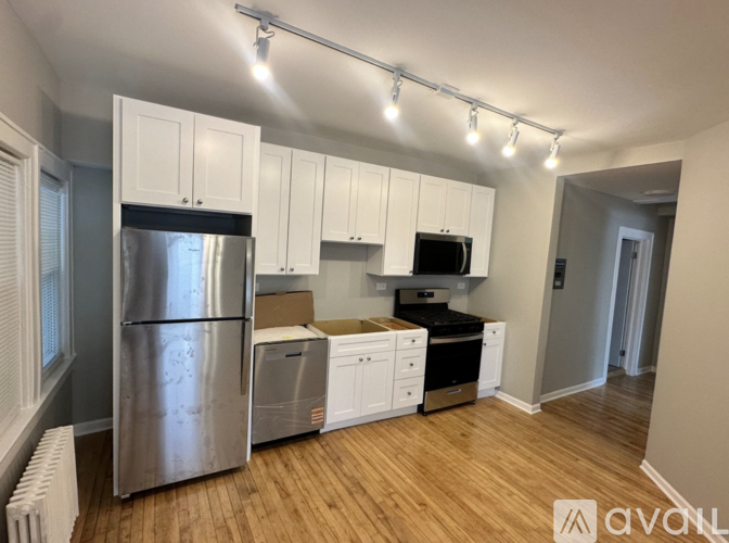 A kitchen with white cabinets and a stainless steel refrigerator.