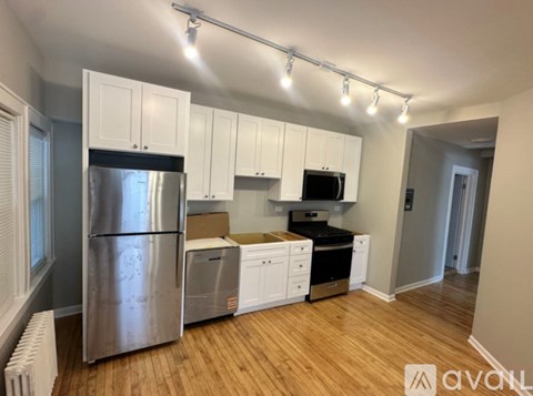 A kitchen with white cabinets and a stainless steel refrigerator.
