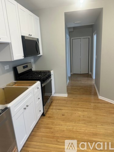 A kitchen with white cabinets and wooden floors.