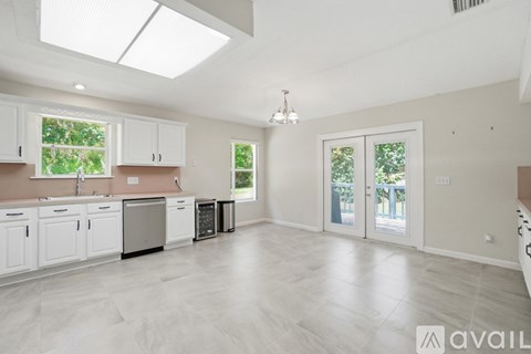 A spacious kitchen with white cabinets and a skylight.