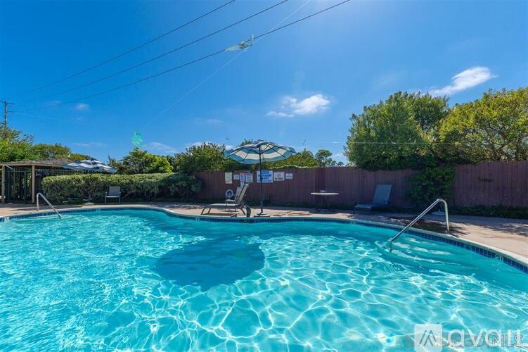 A swimming pool with a blue sky and some trees in the background.