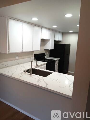A kitchen with white cabinets and a marble countertop.