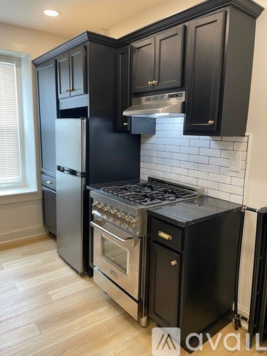 A kitchen with black cabinets and a stainless steel refrigerator.