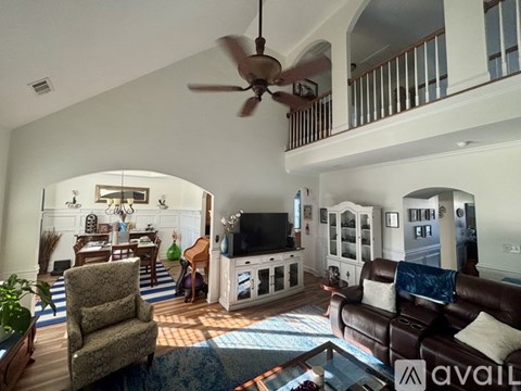 A living room with a brown leather couch and a fan.