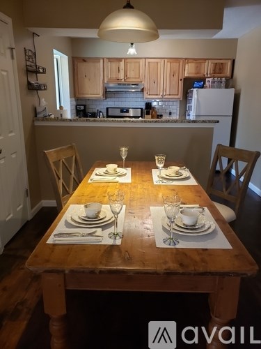 A dining table set for two with a kitchen in the background.