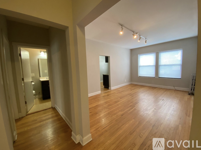 A spacious room with wooden floors and a large window.