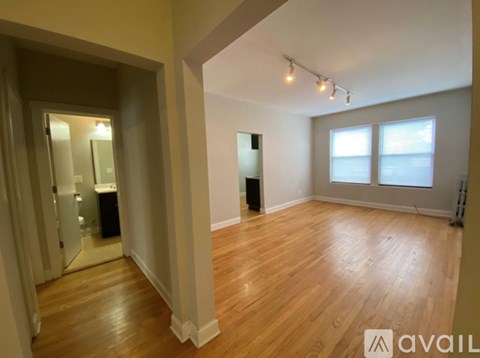 A spacious room with wooden floors and a large window.
