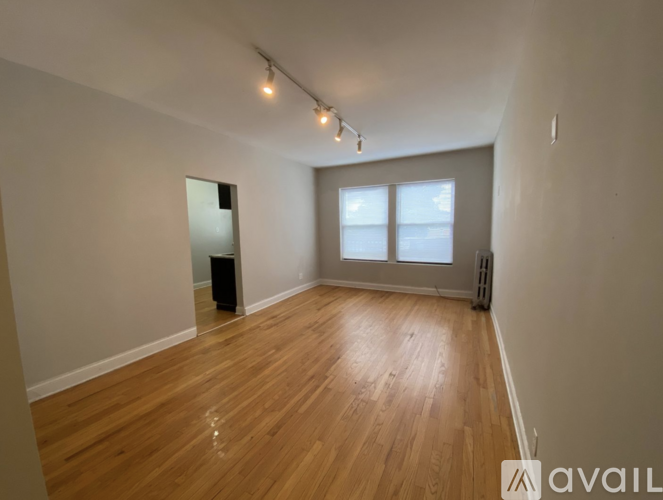 A room with wooden flooring and a window with blinds.