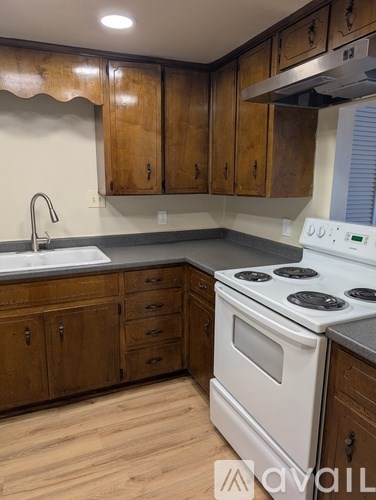 A kitchen with wooden cabinets and a white stove top oven.