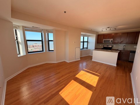 A spacious room with wooden flooring and large windows.