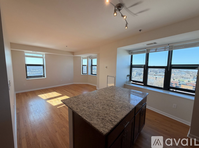 A spacious room with a large island in the middle and windows overlooking a cityscape.