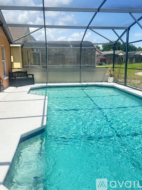 A pool with a glass enclosure and a bench outside a house.